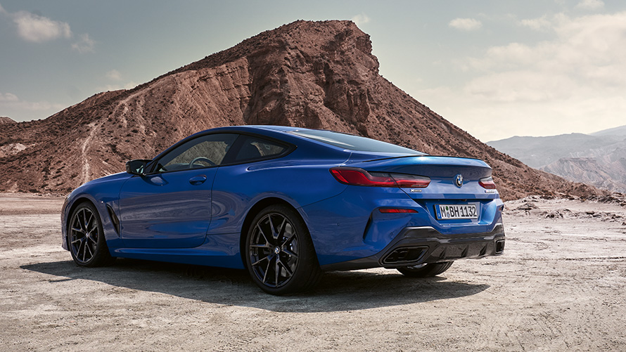 Three-quarter rear view BMW 8 Series Coupé M sport package G15 LCI Facelift 2022 BMW 8 Series Coupé M sport package G15 LCI Facelift 2022 M Portimao Blue metallic three-quarter rear view standing in front of rocks