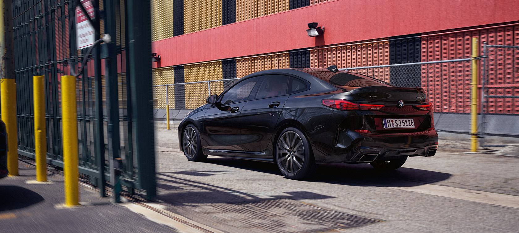BMW M235i xDrive Gran Coupé F44 three-quarter rear view driving BMW M235i xDrive Gran Coupé F44 Black Sapphire metallic three-quarter rear view driving
