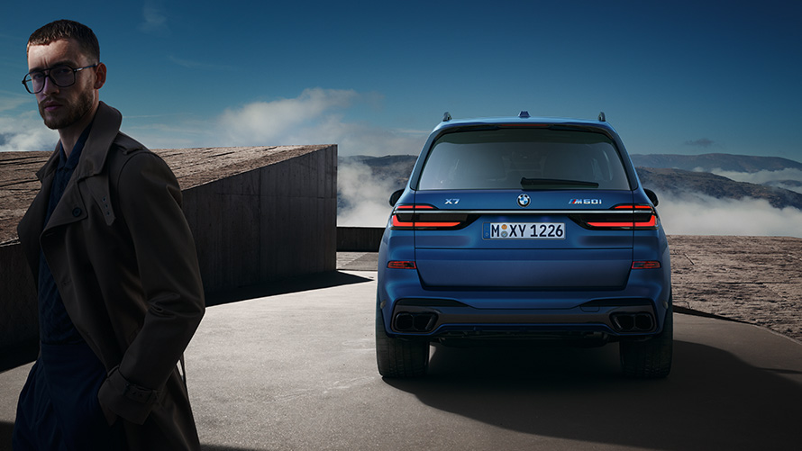 BMW X7 M60i xDrive G07 LCI Frozen Marina Bay Blue rear view standing in front of mountain landscape BMW X7 M60i xDrive G07 LCI Frozen Marina Bay Blue rear view standing in front of mountain landscape with model