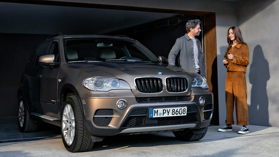 BMW Value Service BMW Value Service BMW X2 G05 Man and woman standing next to BMW vehicle on garage driveway